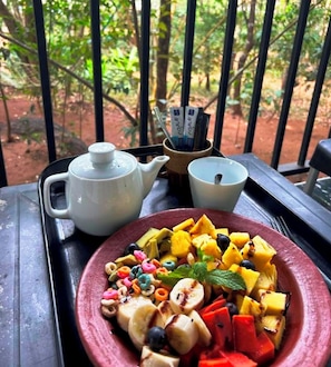 Une table avec une théière, une tasse et une assiette de salade de fruits.