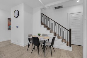 A modern dining area with a table, chairs, and a clock on the wall. - LUX Houston 3BR Close To TMC, NRG, Downtown (Houston)
