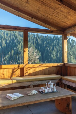 A wooden cabin with a bench and a table set with tea and a book.