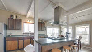 Una cocina con armarios de madera, una campana extractora de acero inoxidable y una zona de bar con taburetes.