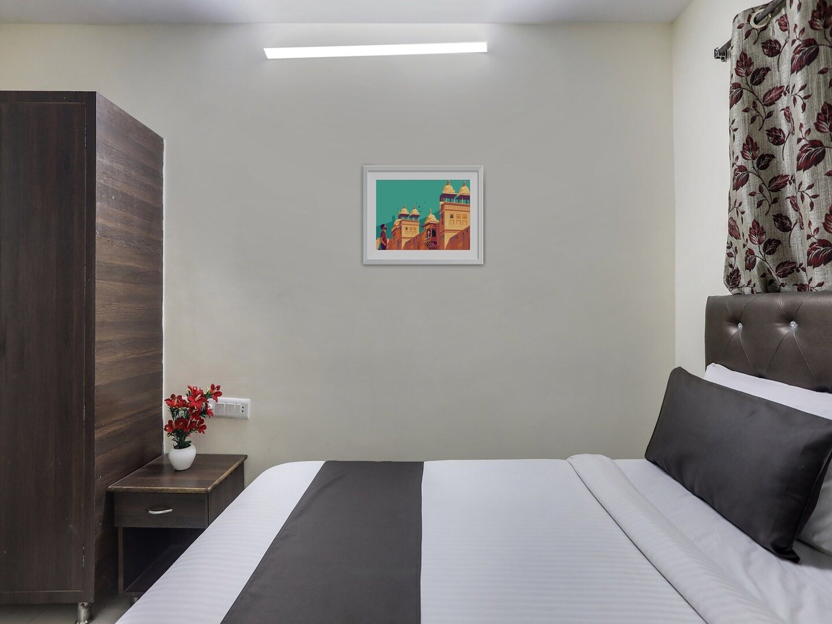 Habitación de hotel con cama, mesita de noche, cómoda y un cuadro en la pared.