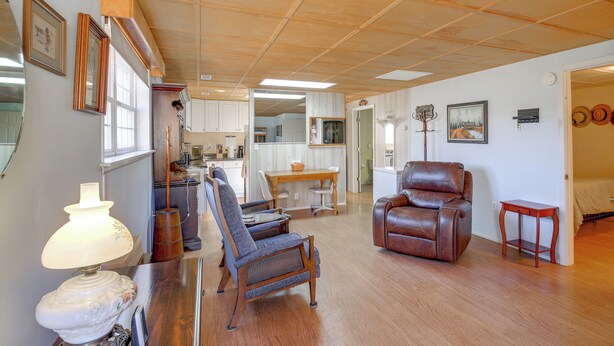 A spacious living room with wooden flooring, a leather armchair, a dining table, and a lamp. - 8 Mi to Appalachian Trail! Home w/ Fire Pit (Ceres)