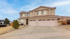 A two-story house with a garage, a driveway, and a small tree. - Extended Stay in Denver! Cozy Apartment w/ Patio (Denver)