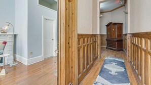 Un corridoio con rivestimenti in legno, un tappeto blu e bianco e un armadietto in legno.