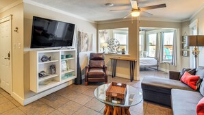 A living room with a television, a brown leather chair, a glass coffee table, and a grey sofa. - Walk to Beach! Pet-Friendly Mustang Island Retreat (Port Aransas)