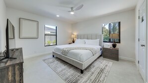 Ein Schlafzimmer mit Bett, Nachttischen, Deckenventilator und Fenster.