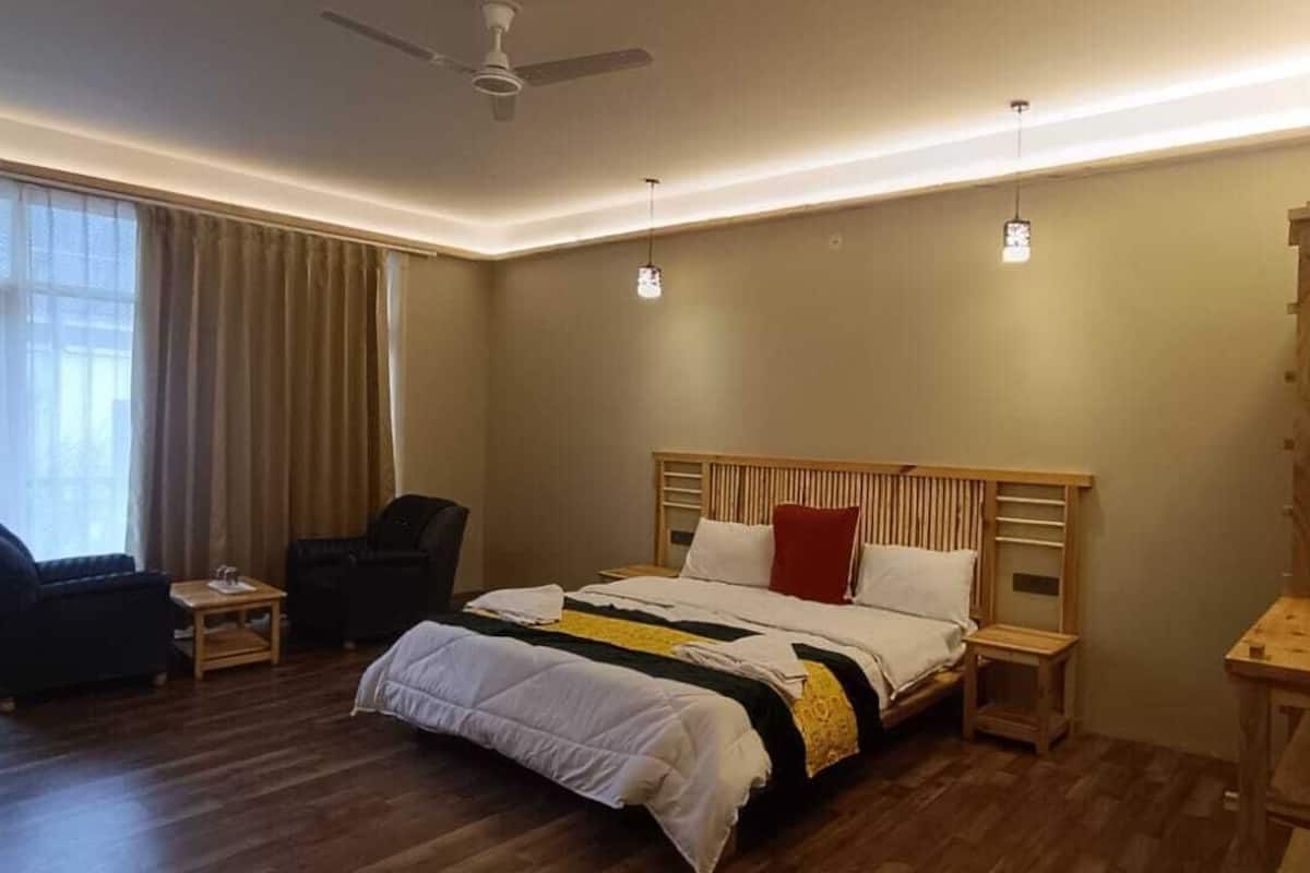 Ein Schlafzimmer mit Bett, Sessel, Schreibtisch und Regale.