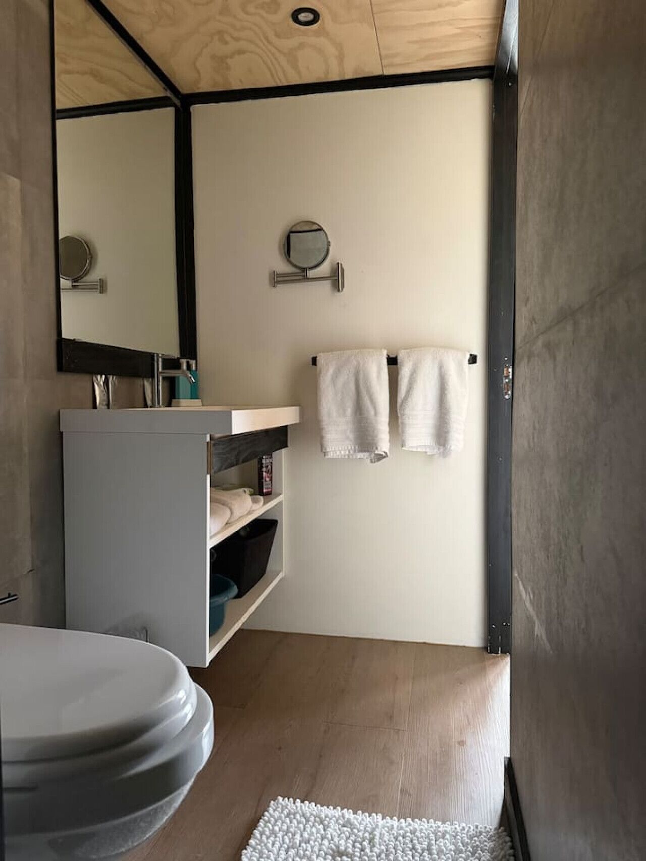 Casa de banho com sanita, lavatório, espelho e porta-toalhas.