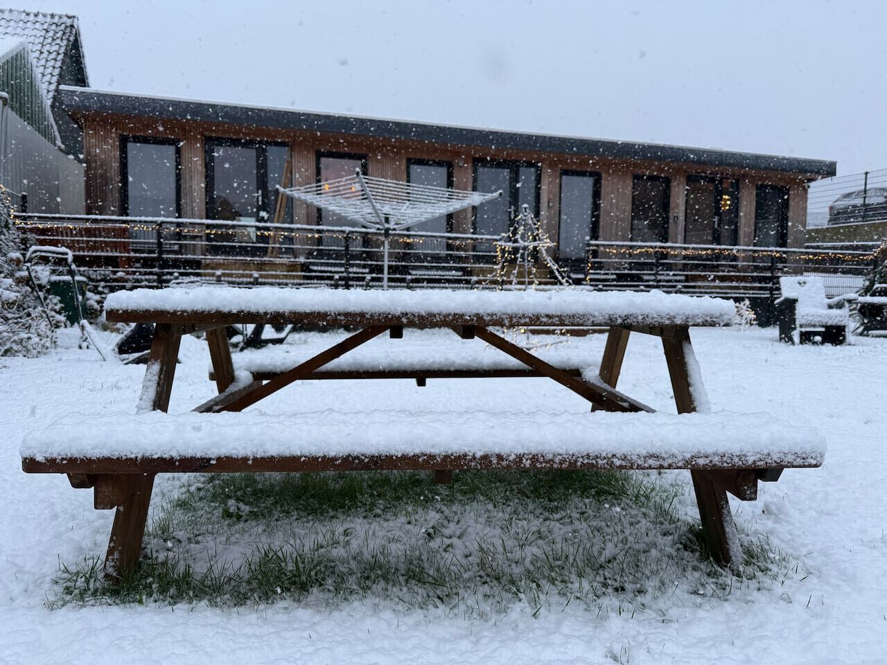 Een sneeuwtje op een picknicktafel voor een gebouw met grote ramen en een balkon.
