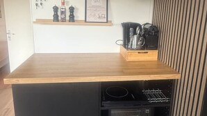 A kitchen area with a wooden countertop, two pendant lights, a coffee machine, and a mini fridge with beverages. - H2, Cozy B&B near Amsterdam - Free parking & Bikes (Lijnden)