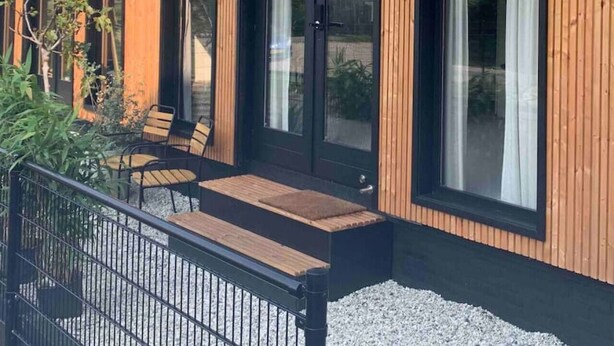 A modern building with large windows, a wooden exterior, and outdoor seating. - H2, Cozy B&B near Amsterdam - Free parking & Bikes (Lijnden)