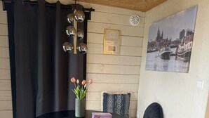 Ein gemütliches Zimmer mit einem runden Tisch, zwei Stühlen, einer Bank, einer Blumenvase, einem gerahmten Zertifikat und einem Stadtbild.
