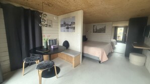 Ein gemütliches Zimmer mit einem runden Tisch, zwei Stühlen, einer Bank, einem Bett und einem Fernseher.
