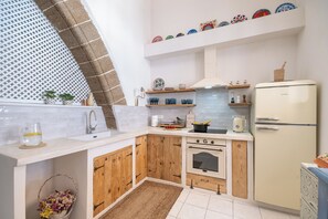 A kitchen with wooden cabinets, a white countertop, a stove, and a refrigerator. - Melenia House (Koskinou)
