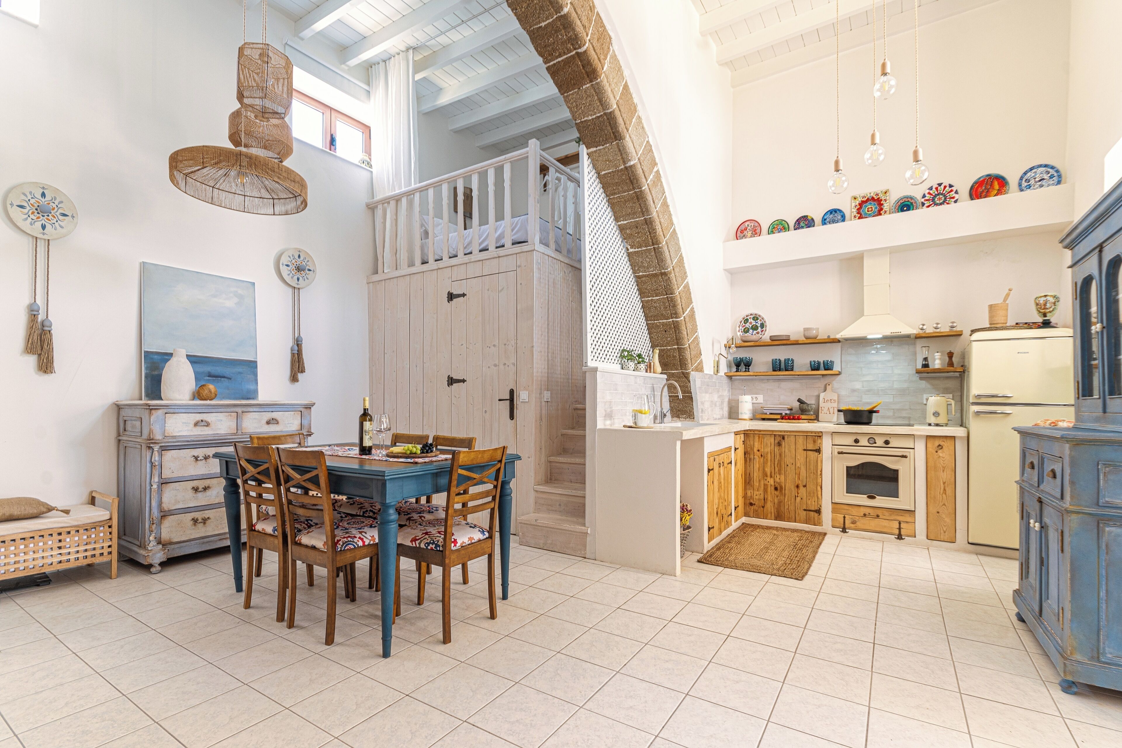 A spacious kitchen with a dining area, wooden cabinets, and a staircase leading to an upper level.