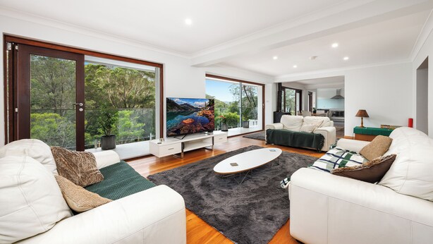 A modern living room with a large TV, comfortable seating, and a view of the outdoors. - Spacious & Sunny House, Fantastic Bush Views, quiet and central location (East Killara)