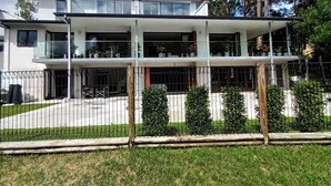 A modern two-story building with balconies, a fenced courtyard, and potted plants. - Spacious & Sunny House, Fantastic Bush Views, quiet and central location (East Killara)