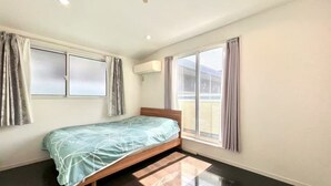 A bedroom with a bed, a window, and an air conditioning unit.