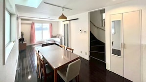 A modern interior with a dining area, a staircase, and a view to another room.