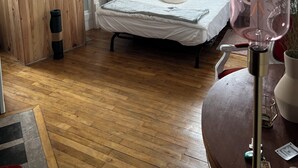 Una camera da letto con un letto, un armadio in legno, un termosifone, una finestra con tende e una lampada a sospensione.