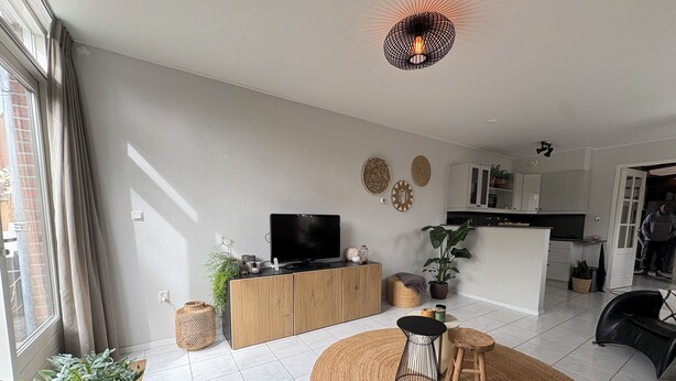 A modern living room with a TV, sofa, and a kitchen in the background. - Holiday home for a family! (Katwijk aan Zee)