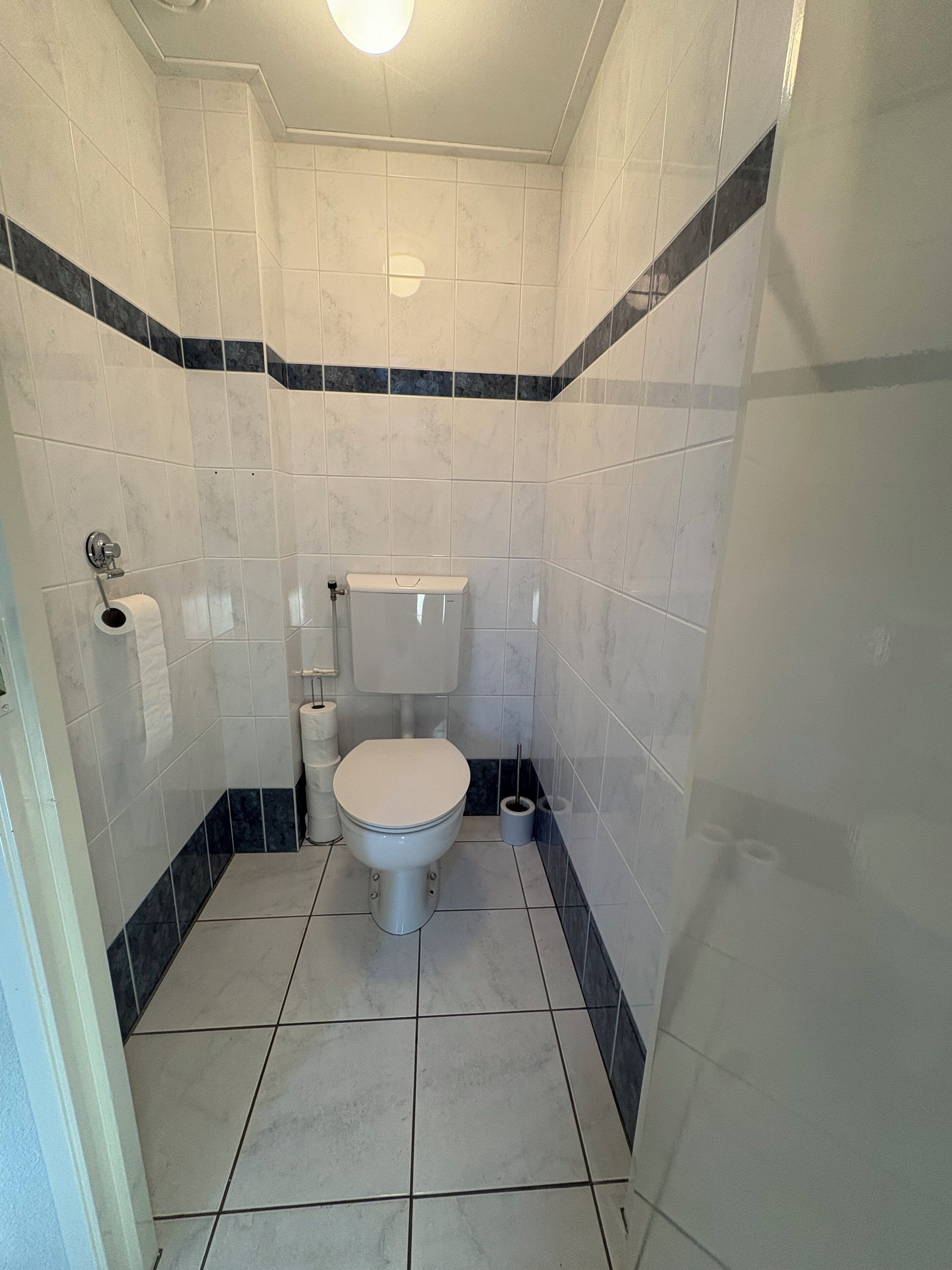 Un baño pequeño y limpio con inodoro, bidé y soporte para papel higiénico.