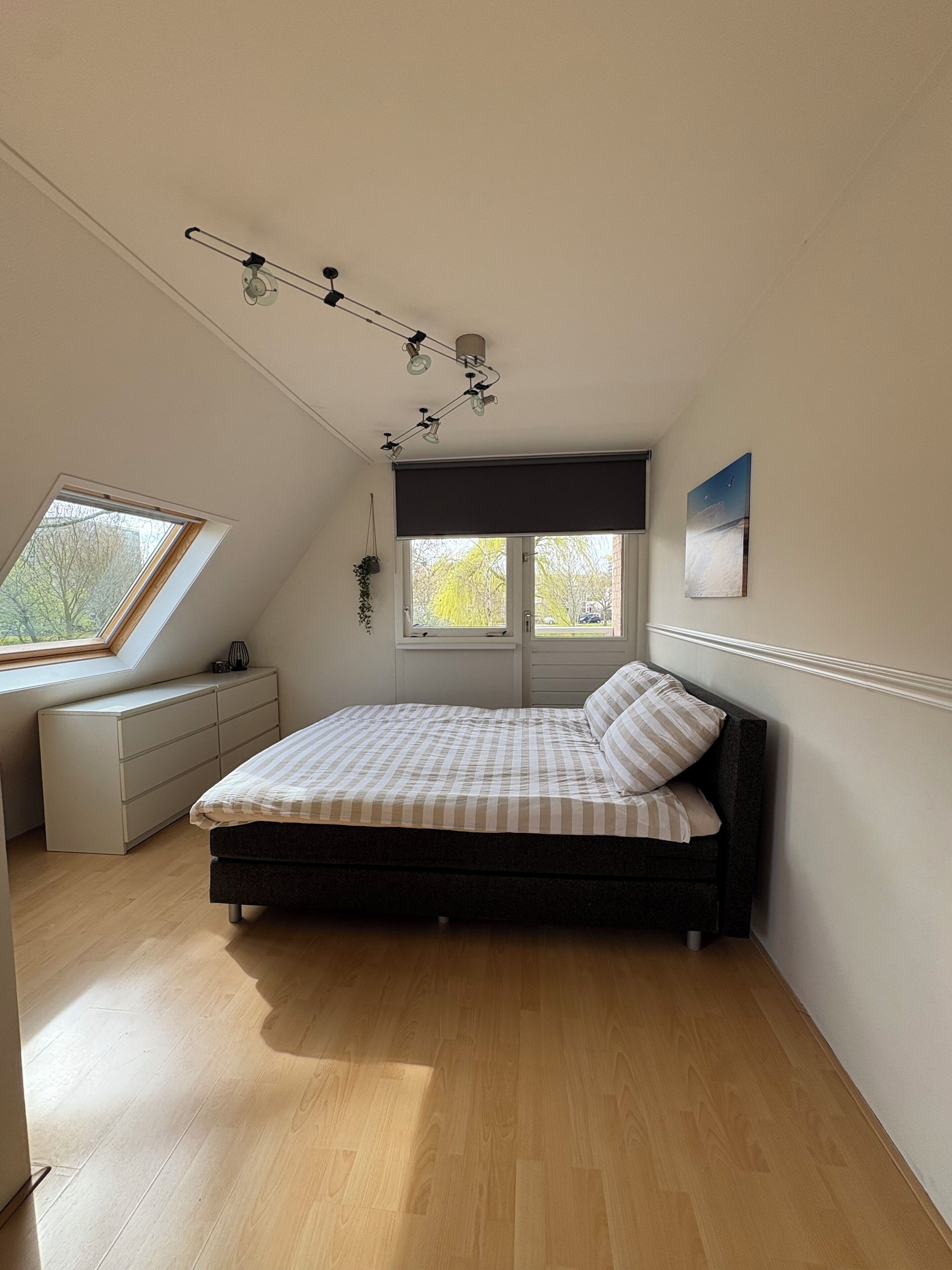 Un dormitorio con una cama, una ventana, un ventilador de techo y una lámpara de pared.