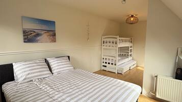 Ein Schlafzimmer mit einem Bett, Etagenbetten, einem Deckenventilator, einer Pendelleuchte, einem Gemälde und einer Heizung.