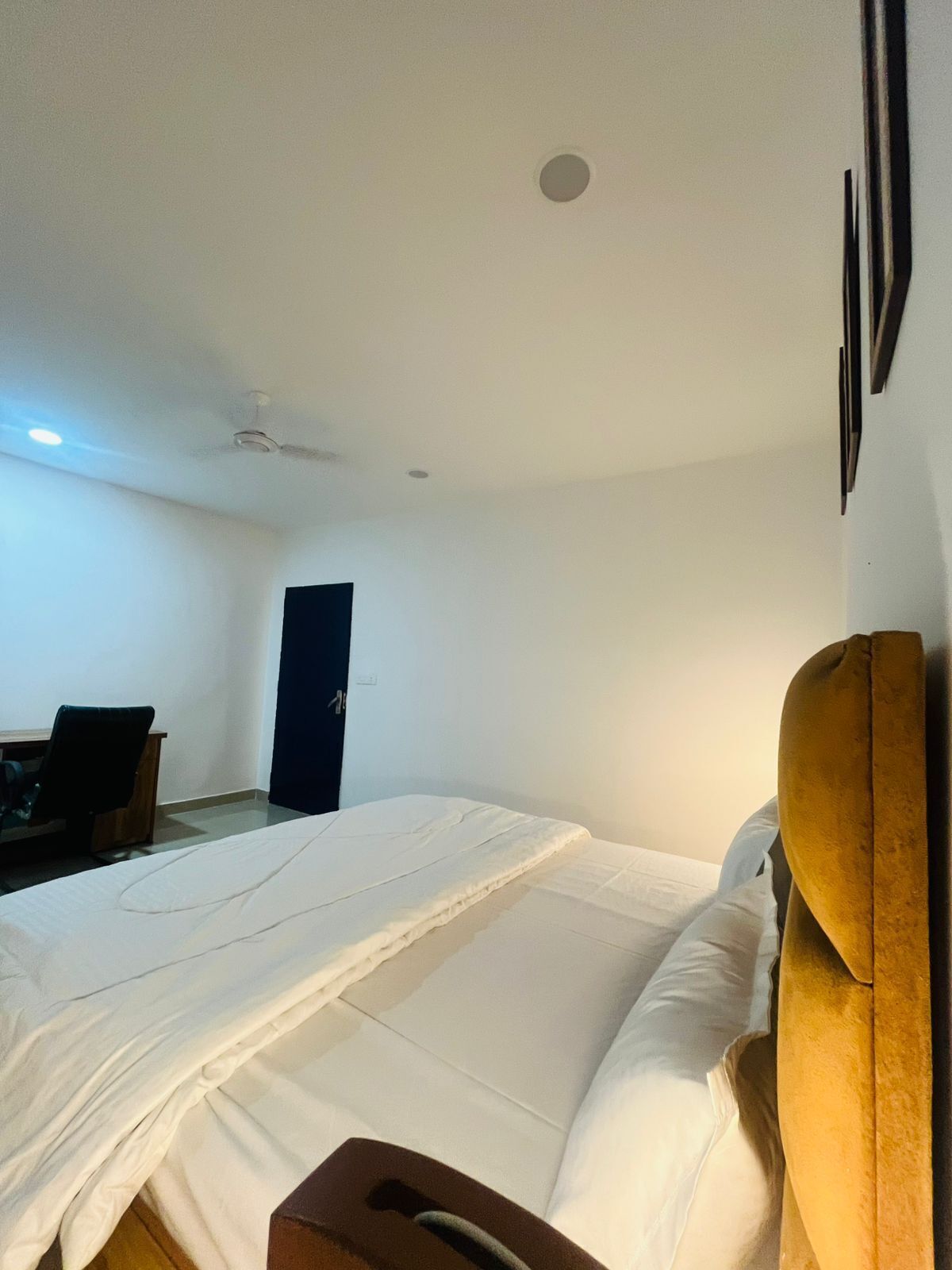 Un dormitorio con cama, una silla, un escritorio y una puerta.
