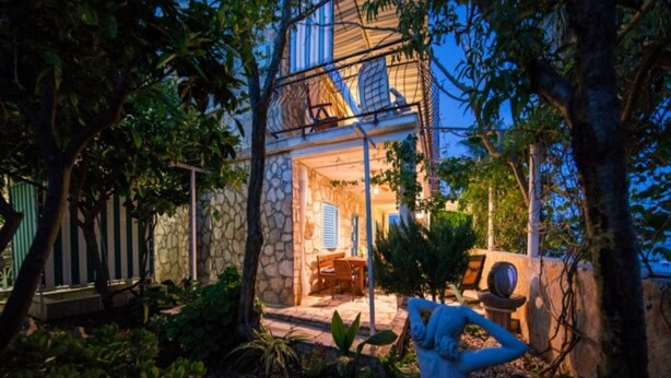 A stone house with a patio, outdoor seating, and a statue. - Golden Coast Apartments (Vis)