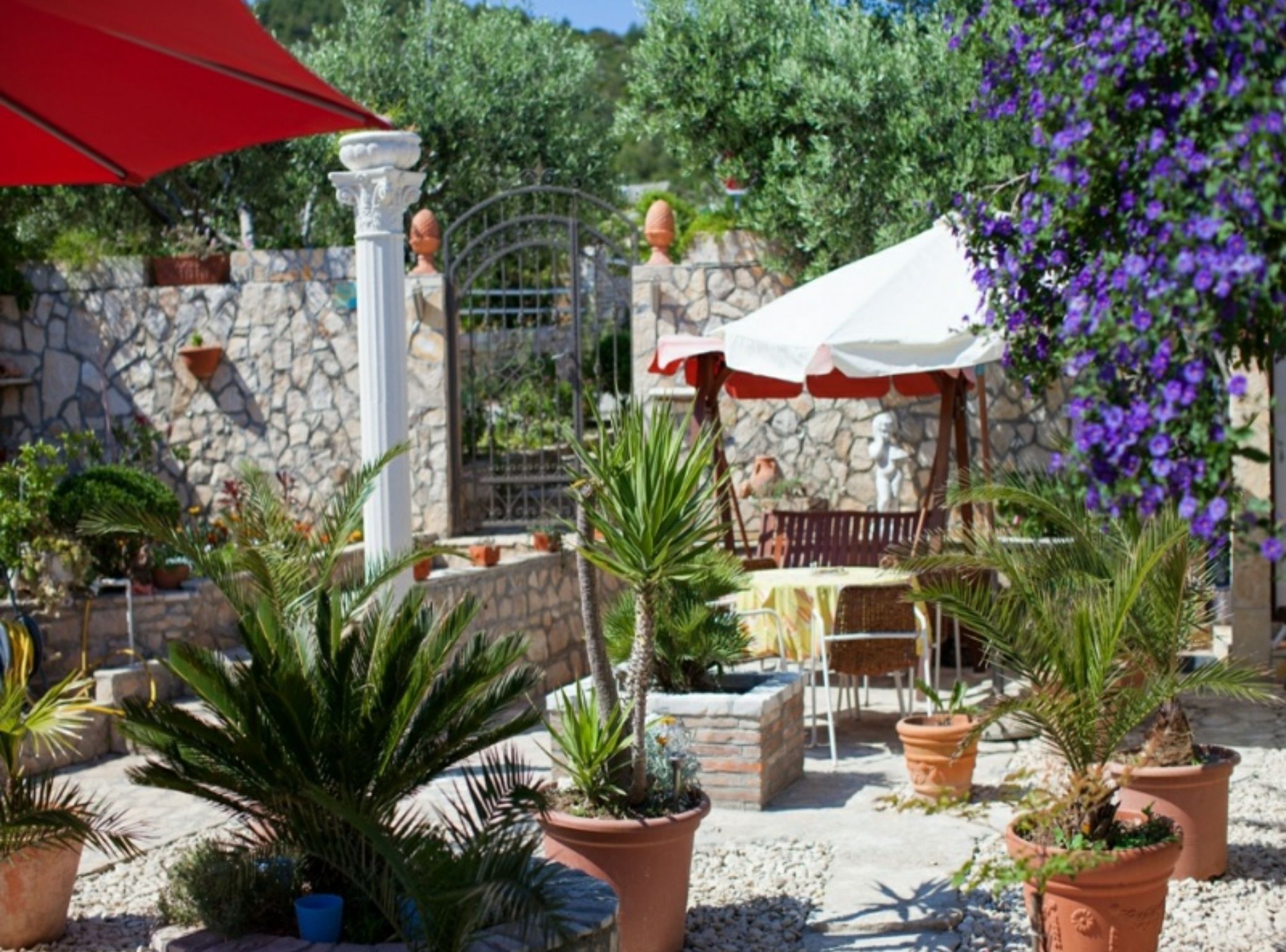 An outdoor patio area with stone walls, potted plants, and outdoor furniture.
