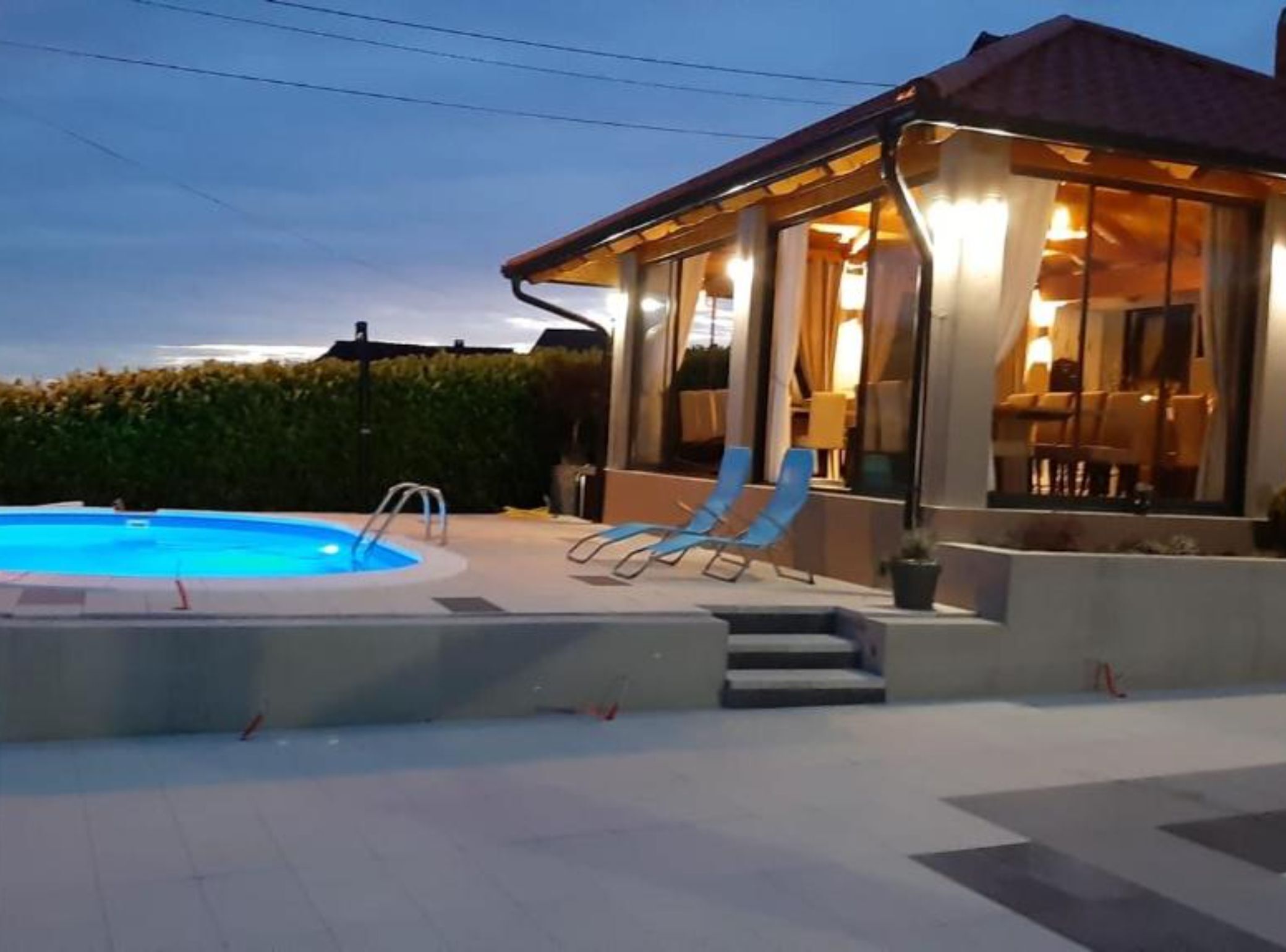Ett område vid poolen med en pool, solstolar och en möblerad sittplats under tak.