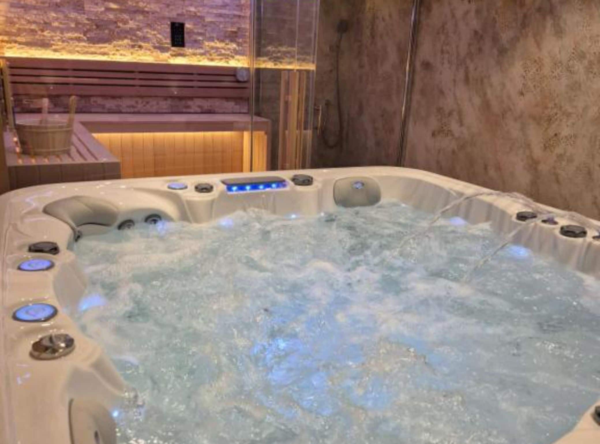 A hot tub with multiple control buttons and a wooden bench in the background.