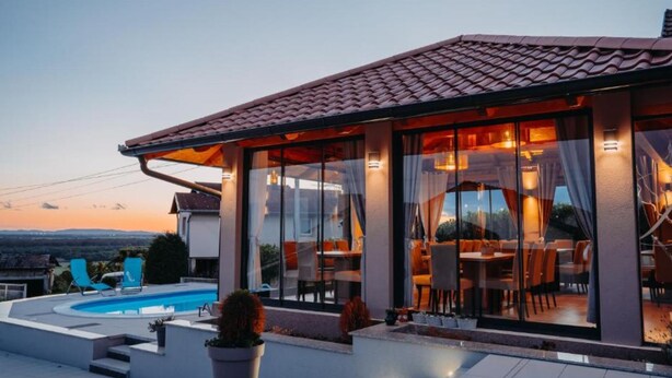 A modern villa with a swimming pool, outdoor seating, and a view of the landscape. - Belajec Wine & Nature Retreat (Popovaca)