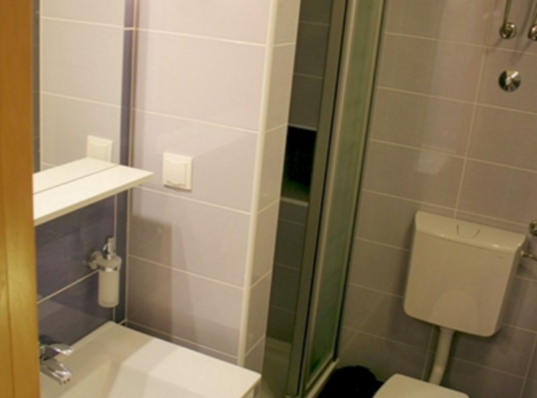 Un baño con cabina de ducha de vidrio, un lavabo blanco y un inodoro.