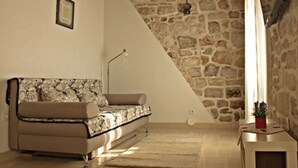 Una habitación acogedora con pared de piedra, un sofá, una mesita con una planta y una lámpara.