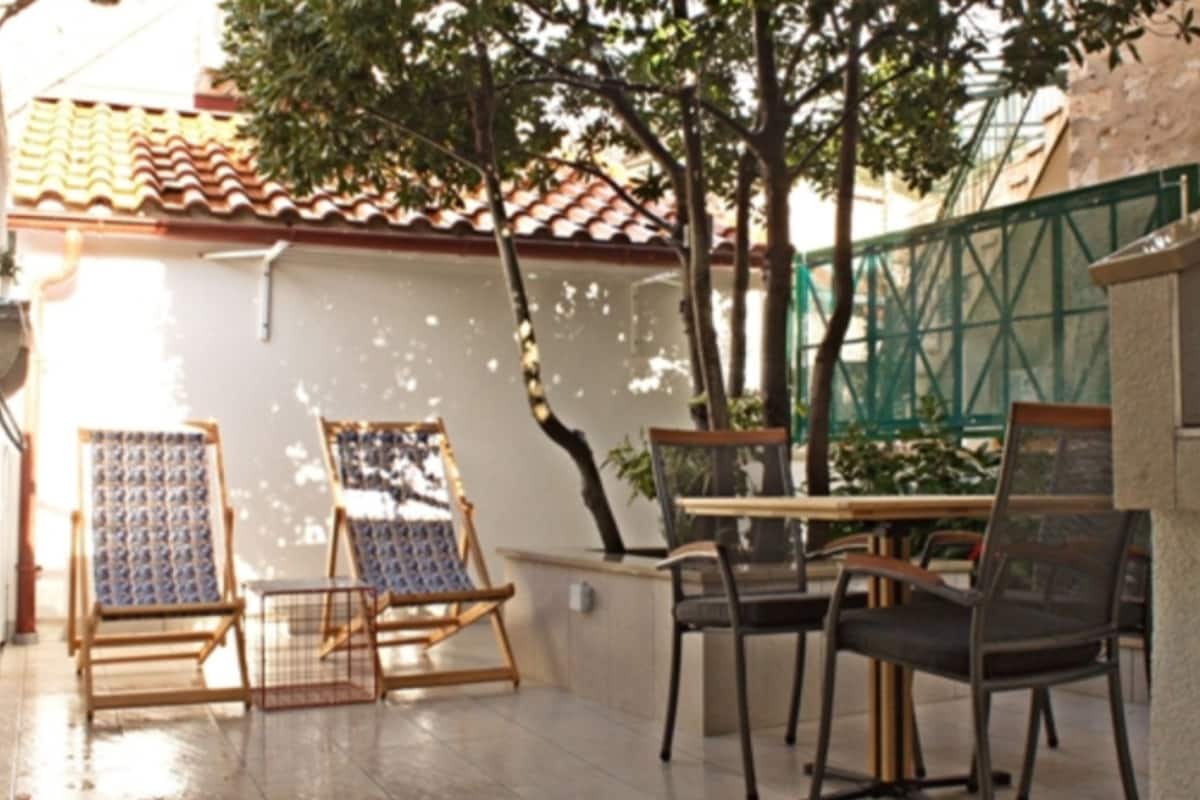 Une terrasse extérieure avec une table et des chaises, une chaise en bois et une chaise en métal.
