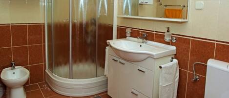 A bathroom with a shower, toilet, sink, and a mirror.