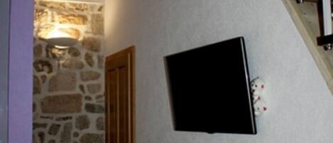 Una habitación con pared de piedra, puerta de madera y un objeto enmarcado en negro en la pared.