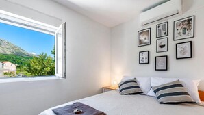 A bedroom with a bed, a window, and a wall with framed pictures. - Lux Holiday Home Maribu (Zupa dubrovacka)