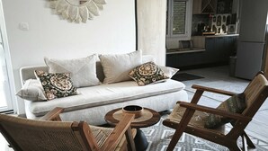 A modern living room with a sofa, two wooden chairs, a coffee table, and a decorative mirror on the wall. - Lux Holiday Home Maribu (Zupa dubrovacka)