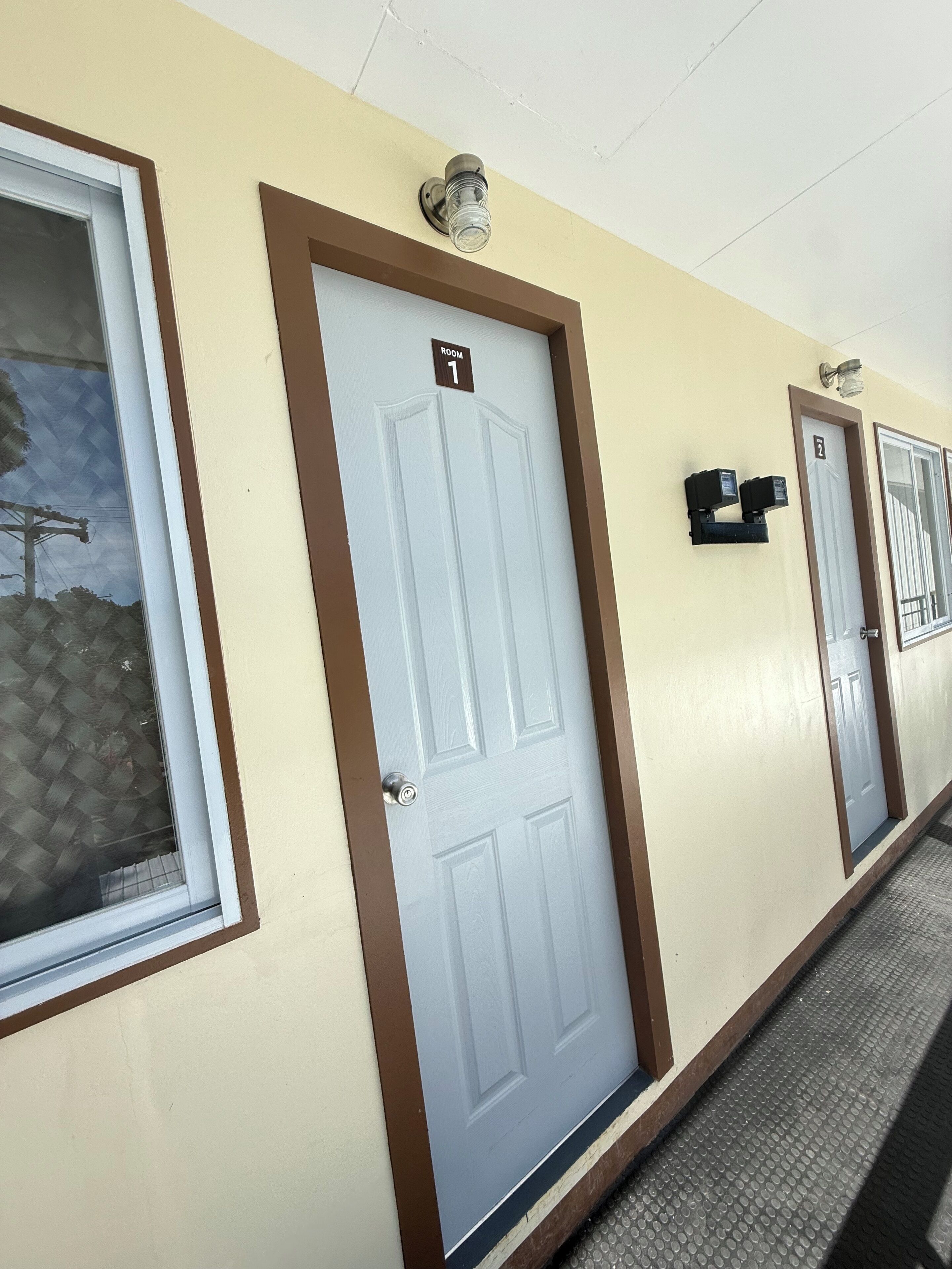 A hotel corridor with doors labeled "Room 1" and "Room 2".