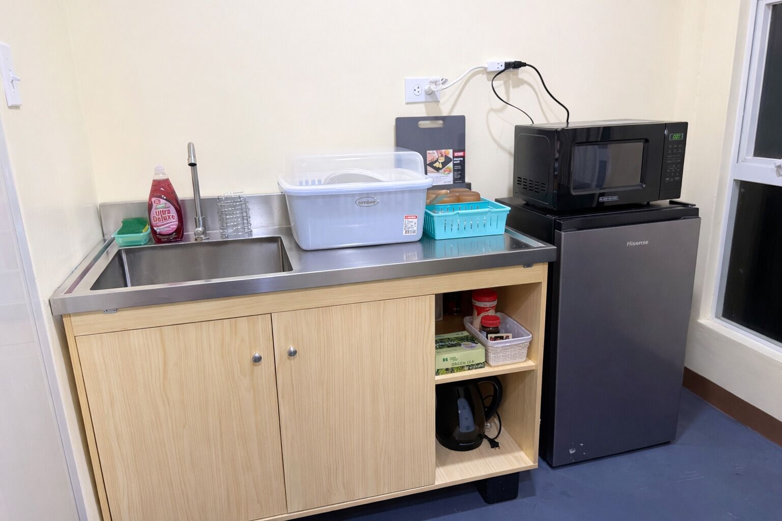 Una kitchenette compacta con un lavamanos, un microondas, un refrigerador y armarios.