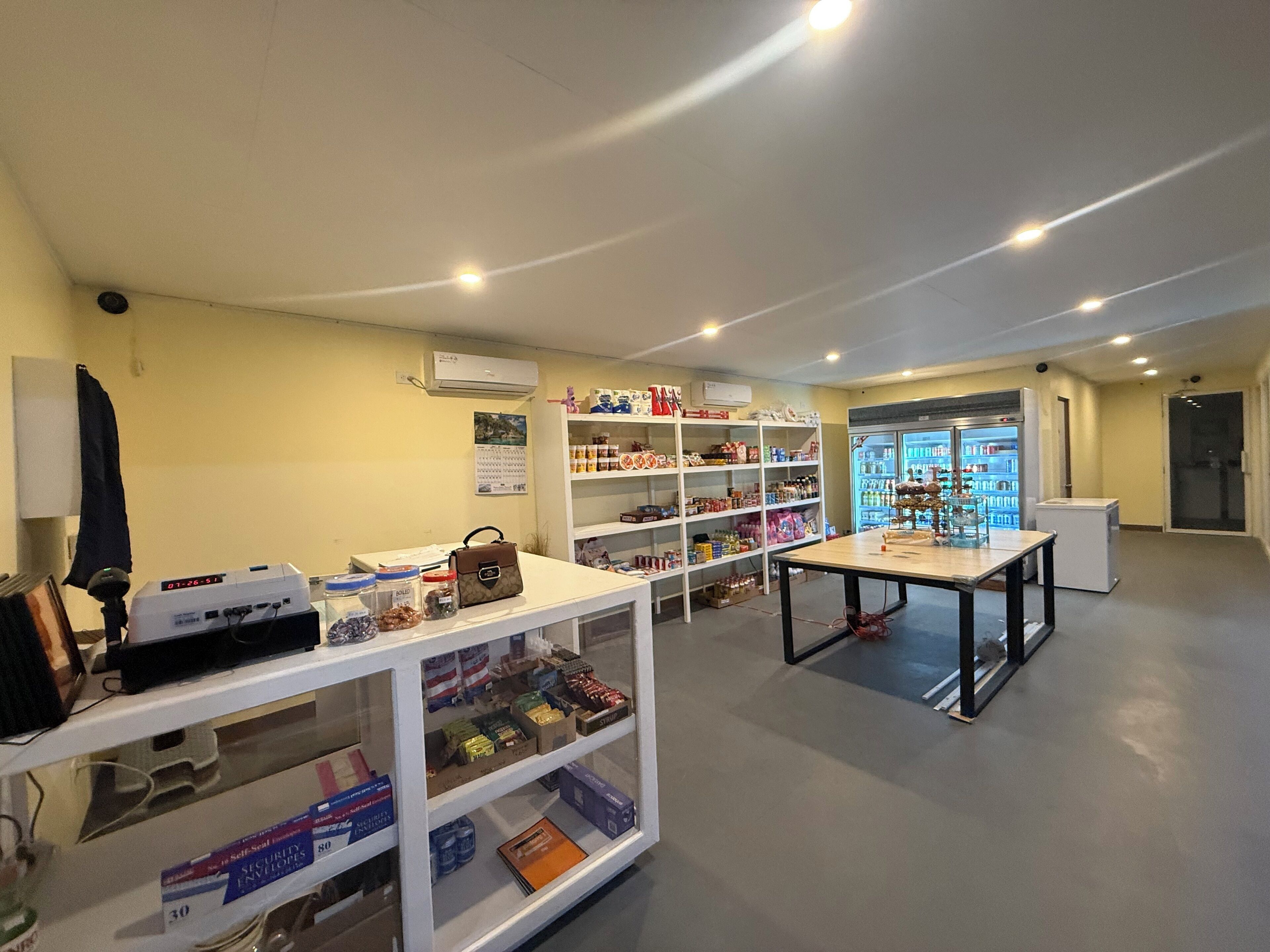 Una habitación con estanterías blancas, una mesa y un refrigerador.
