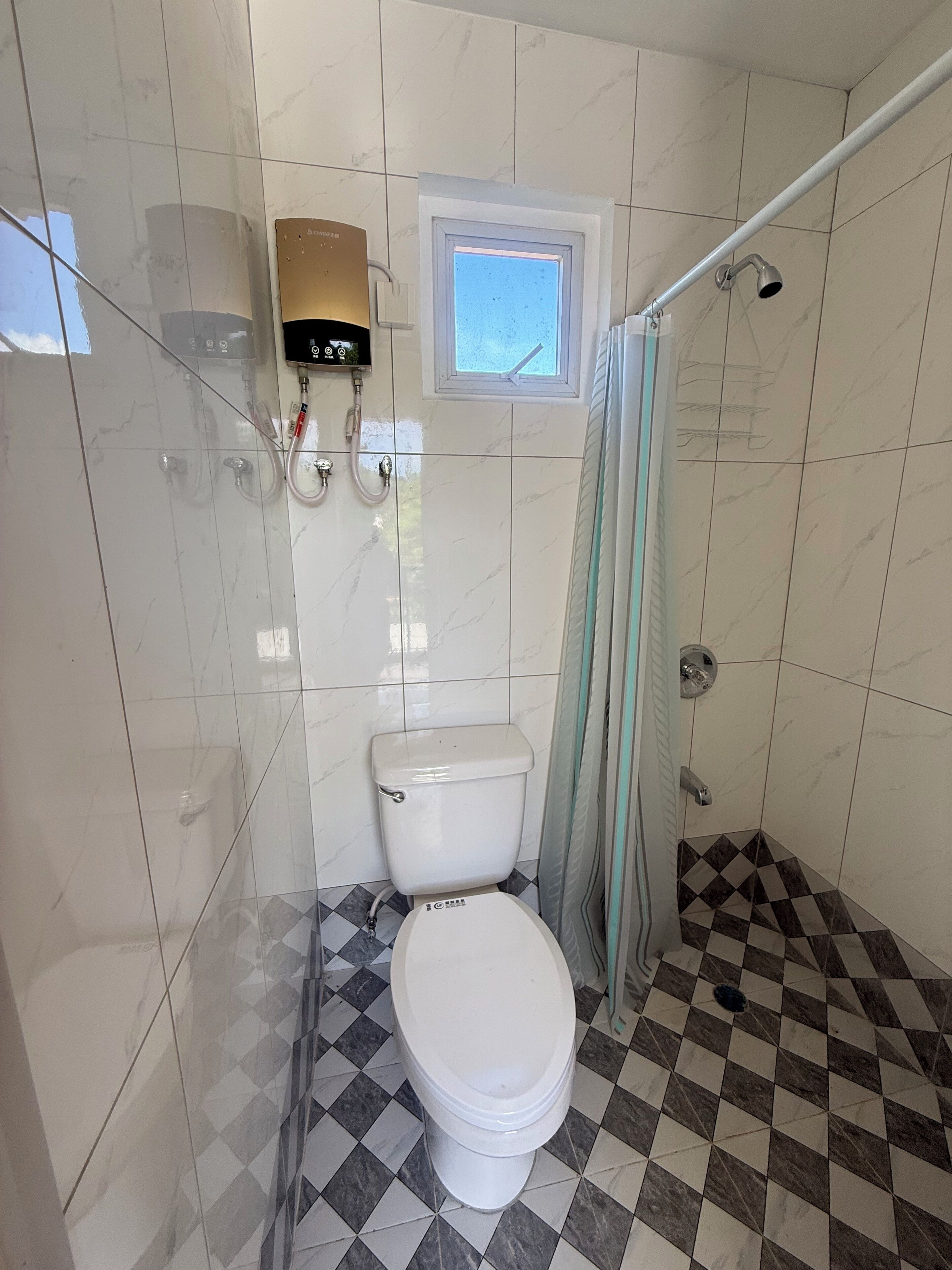 Une salle de bain avec des toilettes, une douche et une fenêtre.