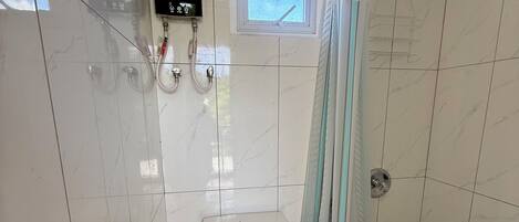 A bathroom with a toilet, a shower, and a window.