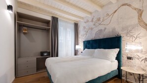 A bedroom with a bed, bedside table, lamp, wardrobe, and a wall with a tree branch design. - Il Vicolo Suite Apartments Cortiletto (Gardola)