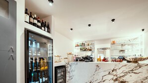 A bar area with a marble countertop, wine bottles, and a refrigerated display. - Il Vicolo Suite Apartments Cortiletto (Gardola)