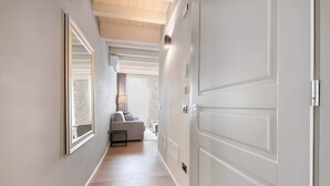 Ein Flur mit heller Wand, einer weißen Tür und einem Sofa im Hintergrund.