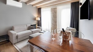 Ein modernes Wohnzimmer mit einer Couch, einem Holzessttisch mit Weingläsern, einem Flachbildfernseher und einer Wand mit Steinverkleidung.
